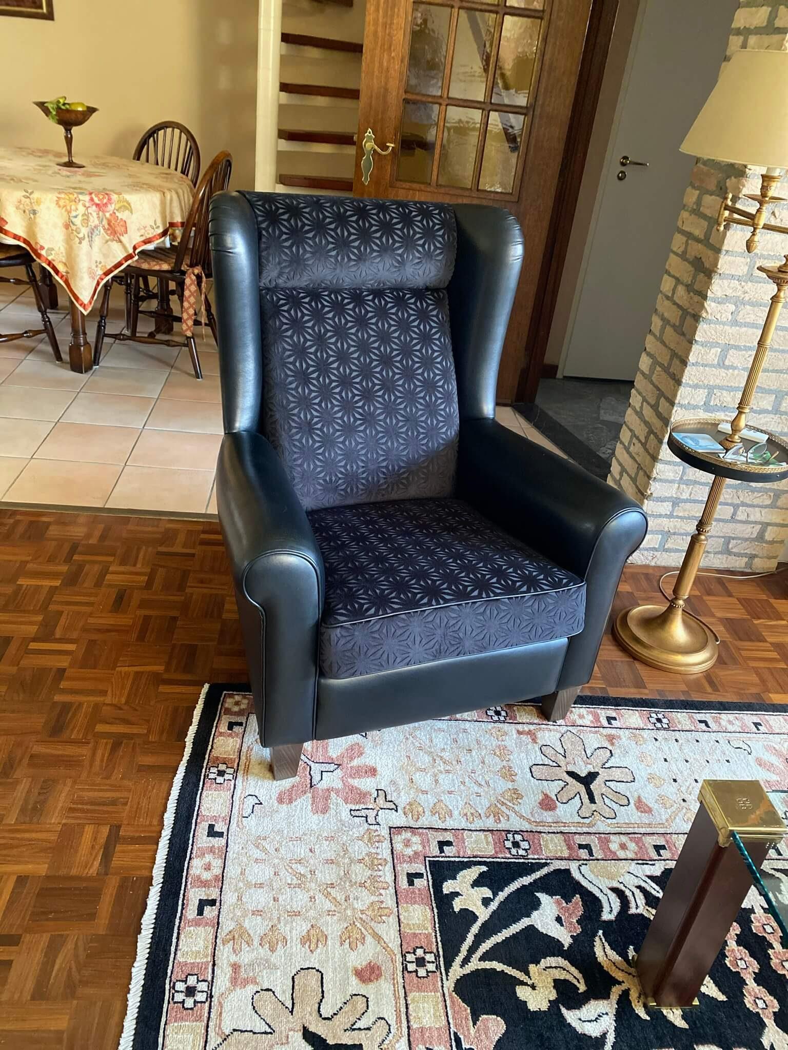 Oorfauteuil in zwart leer met een zitting en rug in donkerblauwe dessinstof