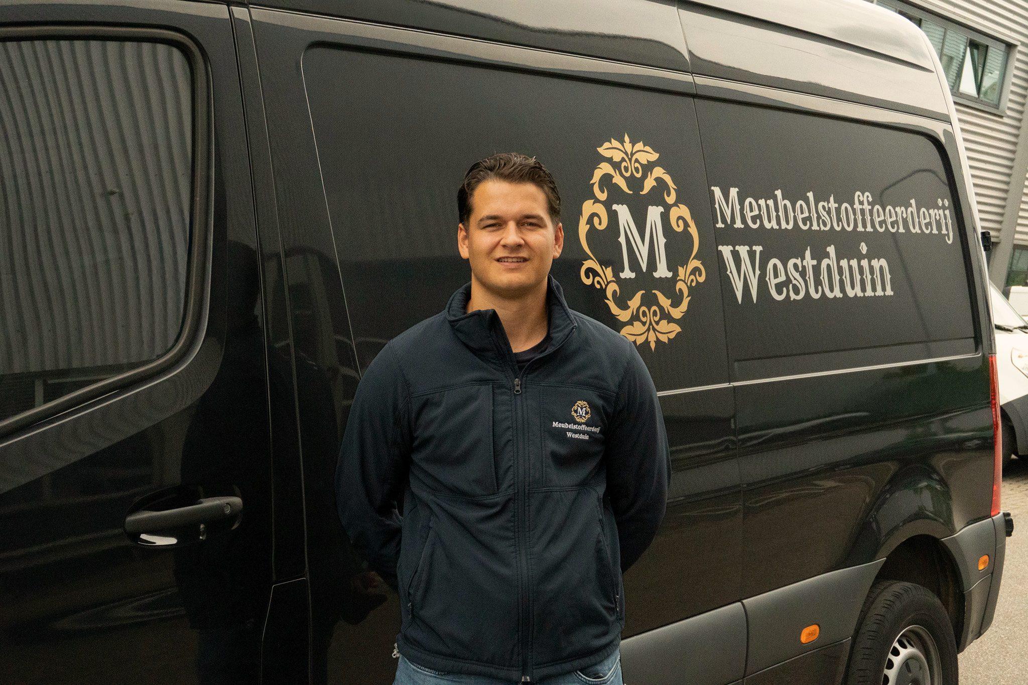 Medewerker van Meubelstoffeerderij Westduin voor de bedrijfsbus met het logo en de naam